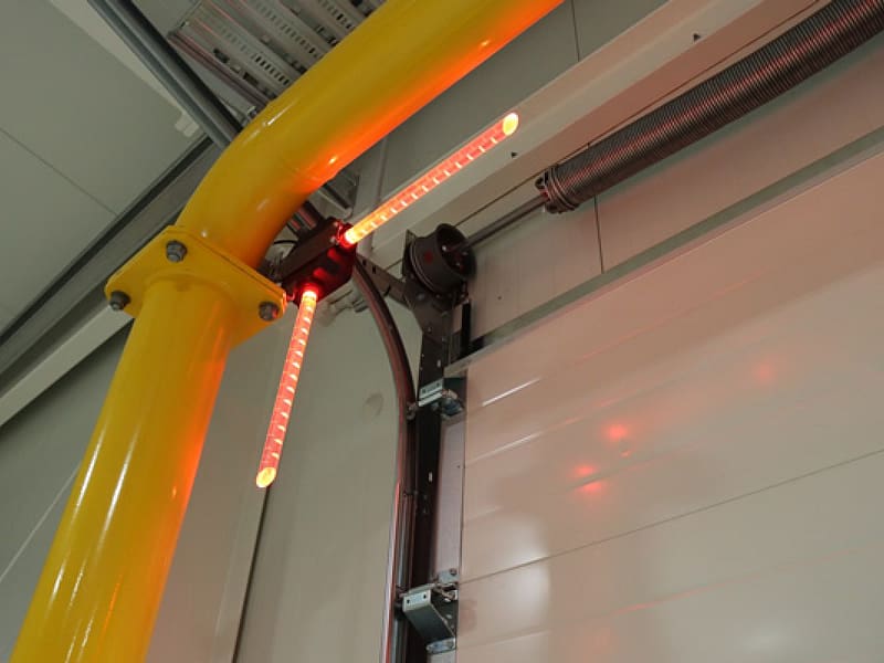 Virtual Vision red LED safety light projecting onto an industrial sectional door.